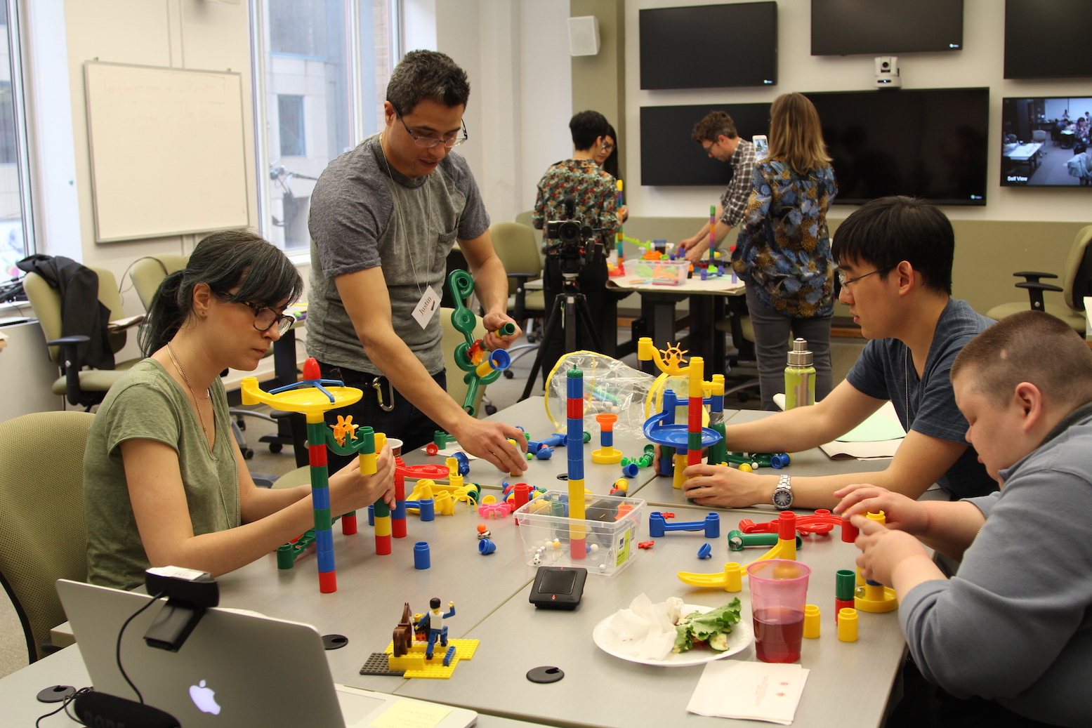 La photographie de quatre personnes qui participent à un créathon avec des jeux
de construction.